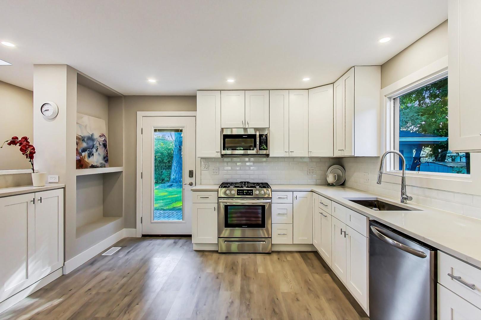 443 Raupp Boulevard Buffalo Grove, IL 60089 - Photo 5 of 21 a kitchen with stainless steel appliances granite countertop a stove a sink and a refrigerator with wooden floors