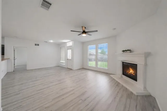 an empty room with wooden floor fireplace and windows