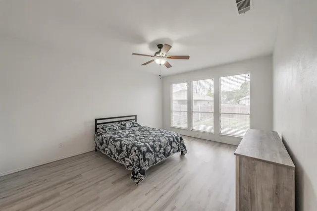 an empty room with chandelier fan and windows