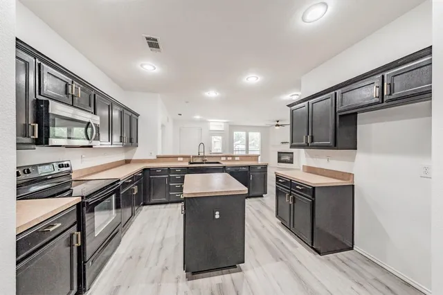 a kitchen with stainless steel appliances granite countertop a stove top oven a sink and a refrigerator