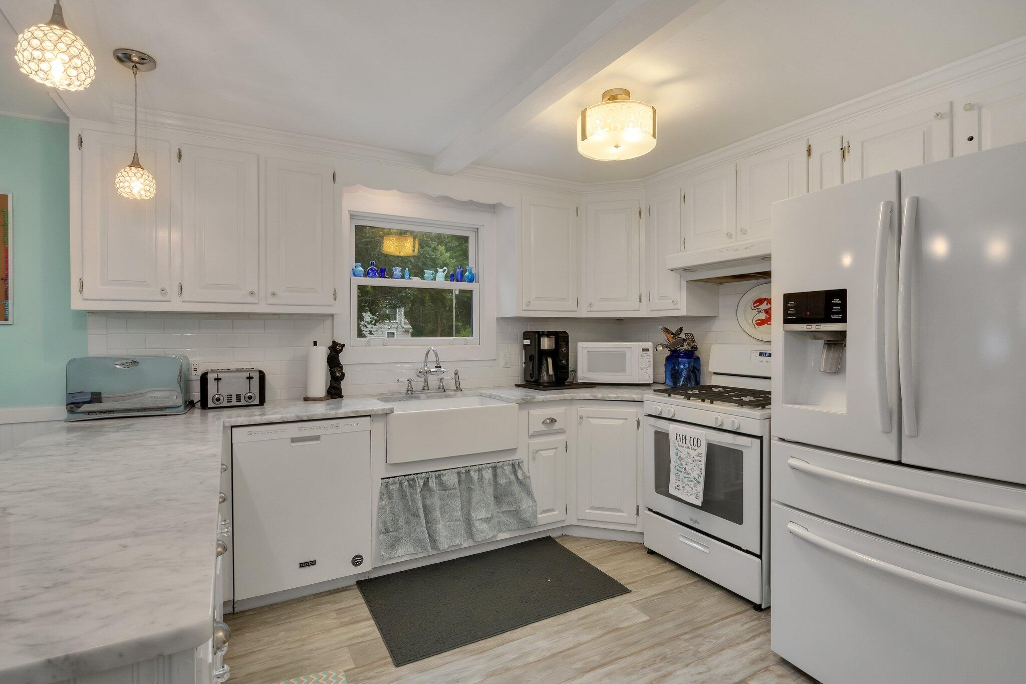 56 Mill Road East Sandwich, MA 02537 - Photo 16 of 63 a white kitchen with stainless steel appliances granite countertop a stove a sink dishwasher and a refrigerator with wooden floor