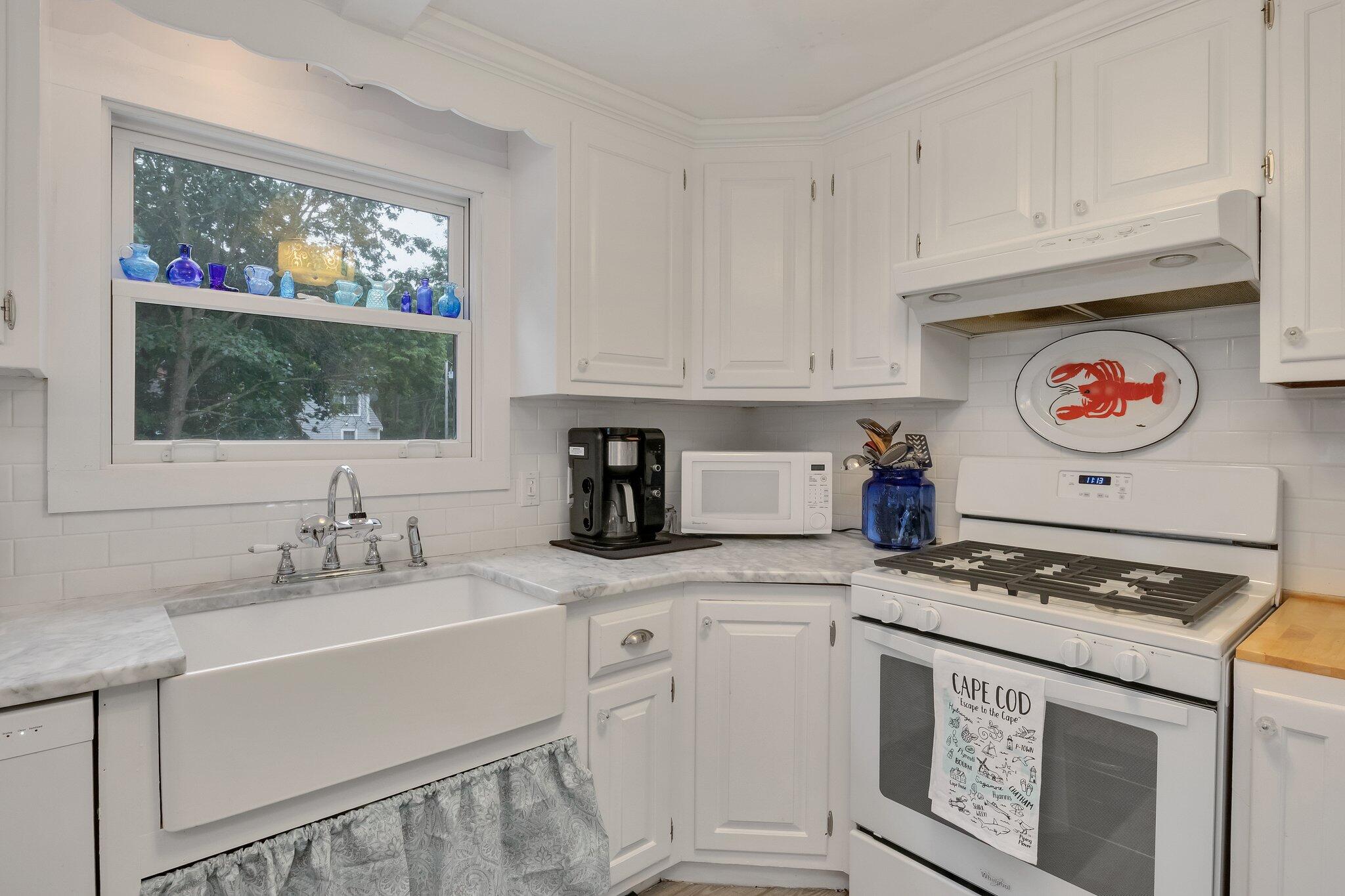 56 Mill Road East Sandwich, MA 02537 - Photo 18 of 63 a kitchen with granite countertop a stove a sink dishwasher and white cabinets with wooden floor
