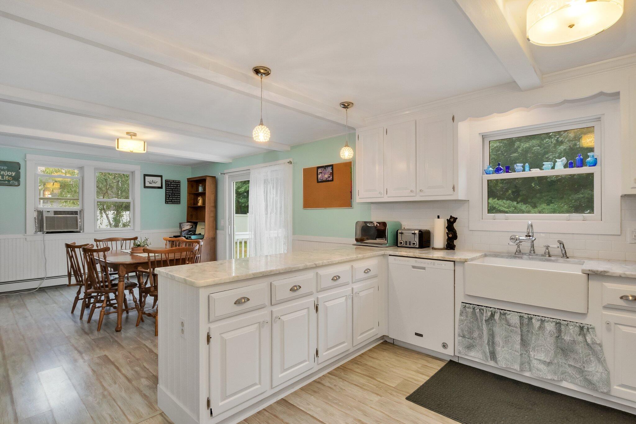 56 Mill Road East Sandwich, MA 02537 - Photo 20 of 63 a large white kitchen with cabinets a sink a window and chairs