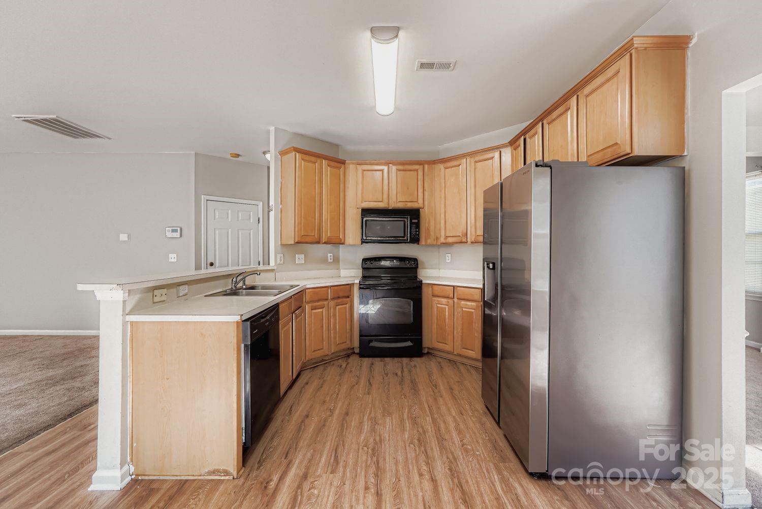 11609 Erwin Ridge Avenue Charlotte, NC 28213 - Photo 6 of 29 a kitchen with a refrigerator a stove top oven a sink dishwasher and wooden cabinets