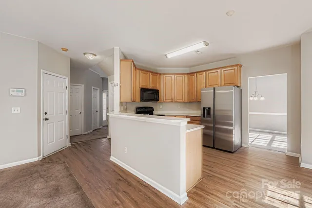 a kitchen with a refrigerator a stove top oven and wooden floor
