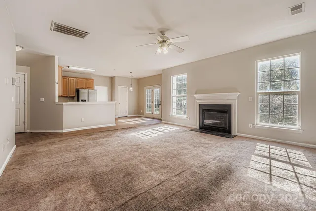 an empty room with windows and fireplace
