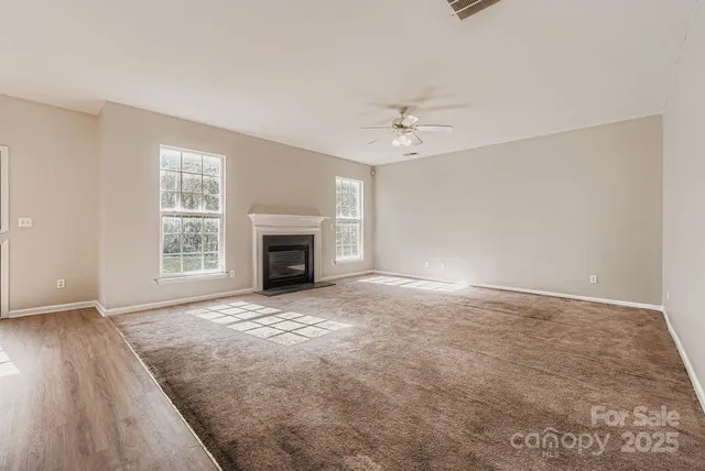 a view of empty room with fireplace and wooden floor