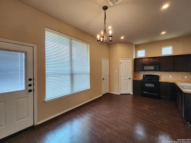 a kitchen with stainless steel appliances granite countertop a refrigerator a sink dishwasher a stove and a wooden floor