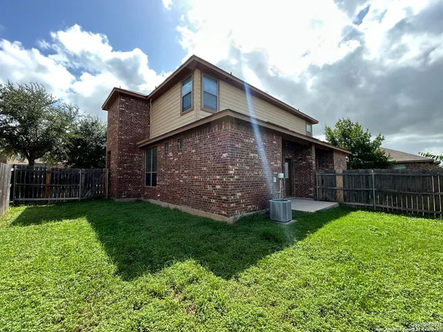 a view of a house with brick walls and a yard with wooden fence