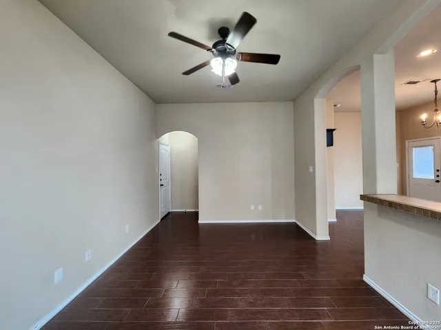 an empty room with wooden floor and a ceiling fan