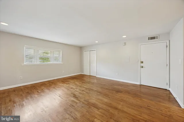 a view of an empty room with wooden floor and a window