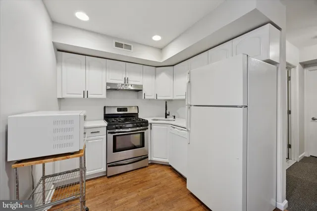 a kitchen with stainless steel appliances white cabinets and a refrigerator