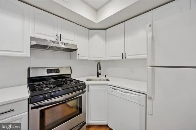 a kitchen with stainless steel appliances white cabinets and a stove top oven