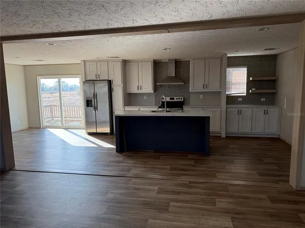a kitchen with stainless steel appliances granite countertop a refrigerator a sink dishwasher and a stove with wooden floor