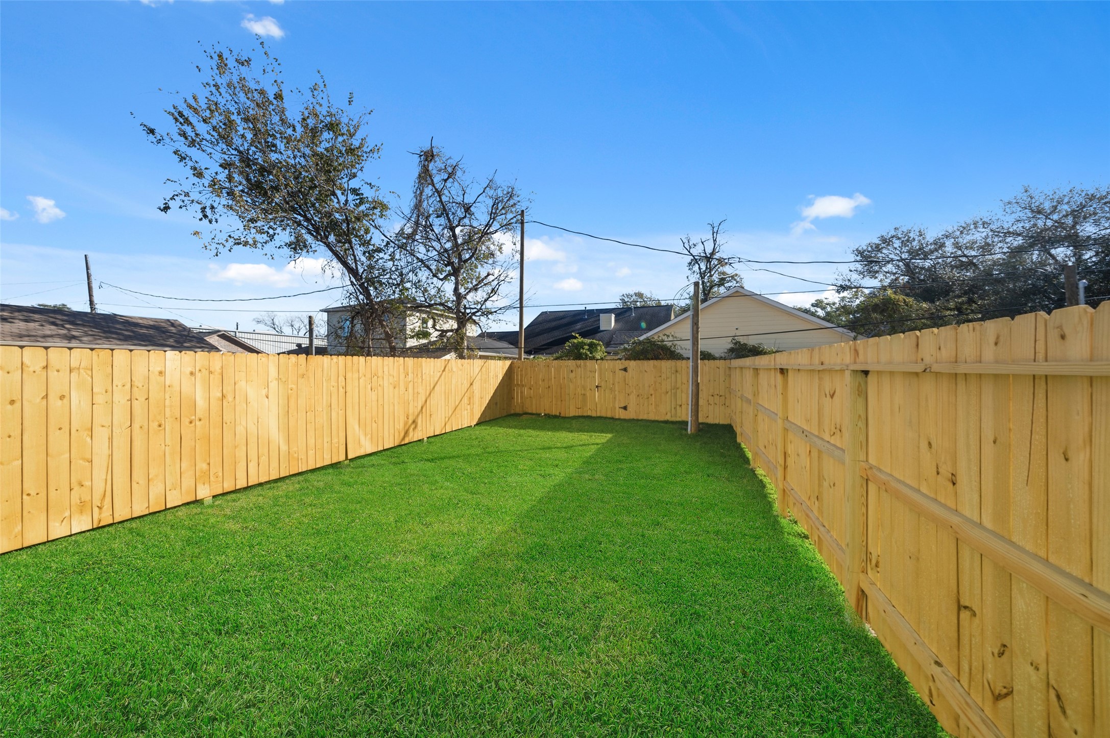 3422 Elser Street Houston, TX 77009 - Photo 3 of 26 A spacious backyard with lush green grass, enclosed by a wooden privacy fence, perfect for outdoor activities and gardening.