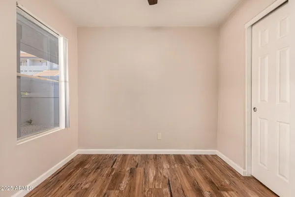 a view of an empty room with wooden floor and a window
