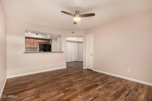 a view of an empty room with wooden floor and a ceiling fan
