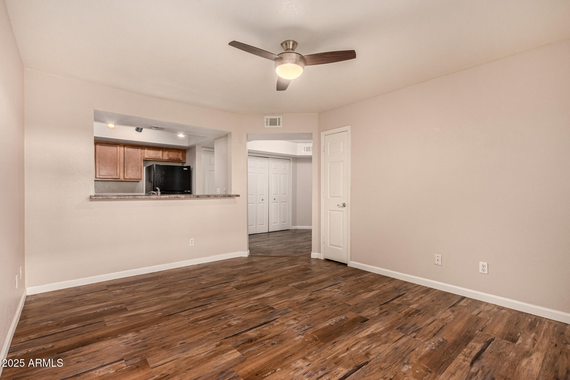 1331 West Baseline Road, Unit 167 Mesa, AZ 85202 - Photo 9 of 42 a view of an empty room with wooden floor and a ceiling fan