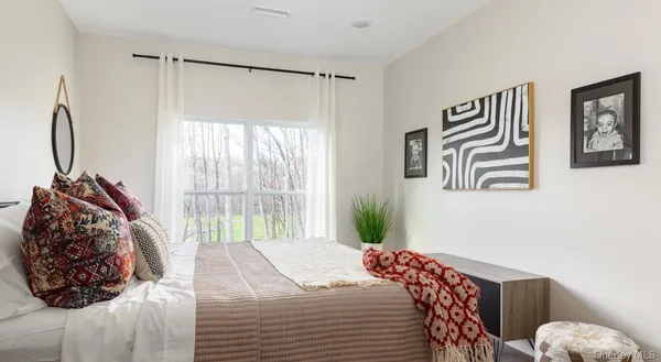 a bedroom with a bed and a large mirror next to a window