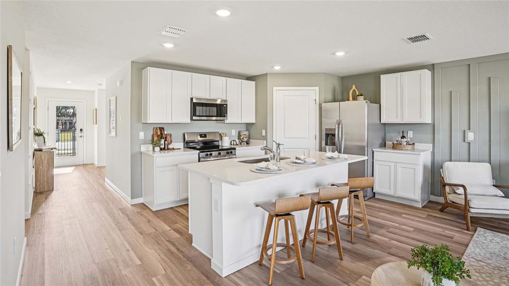 15880 Southeast 101st Ct Road Summerfield, FL 34491 - Photo 2 of 32 a kitchen with stainless steel appliances a microwave a stove a refrigerator a sink a dining table and chairs with wooden floor