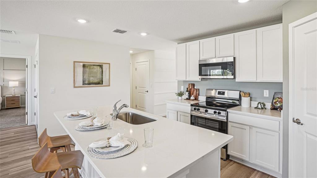15880 Southeast 101st Ct Road Summerfield, FL 34491 - Photo 8 of 32 a kitchen with stainless steel appliances a white table and chairs in it