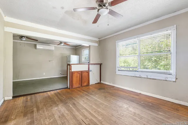 a view of empty room with wooden floor and fan