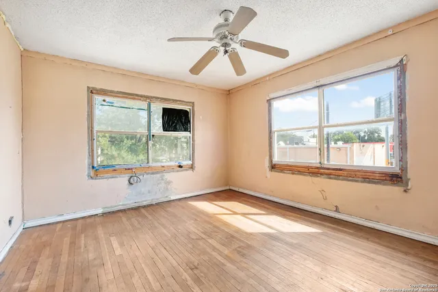 a view of an empty room with a window and wooden floor