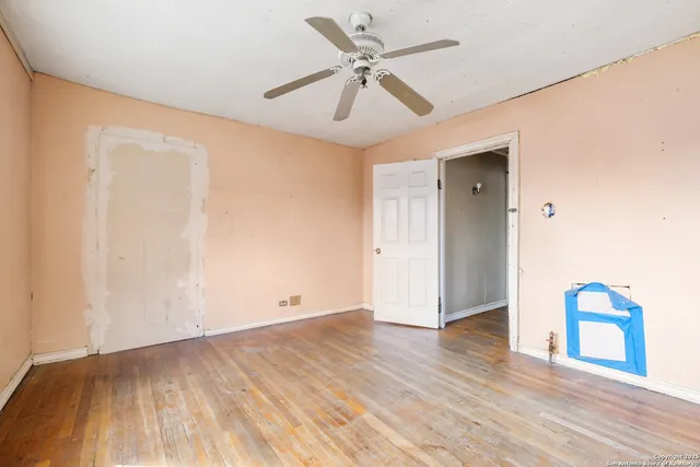 an empty room with wooden floor and ceiling fan