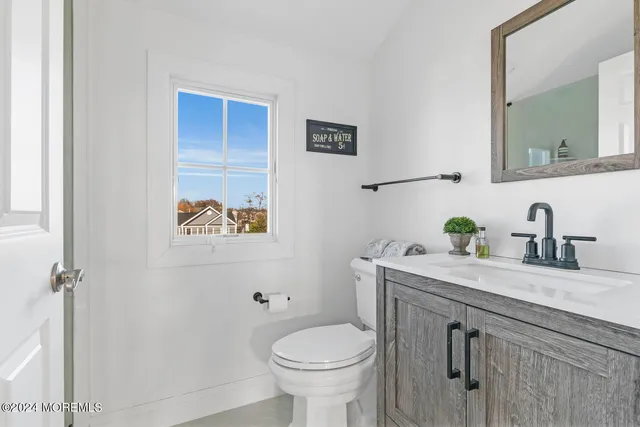 a bathroom with a granite countertop toilet sink and mirror
