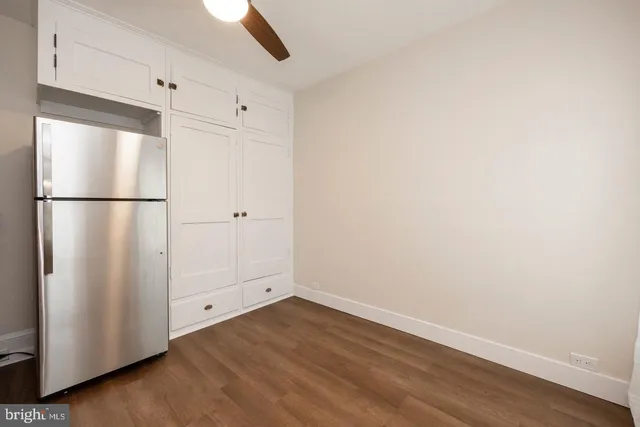 a view of a refrigerator in kitchen with white wooden cabinets