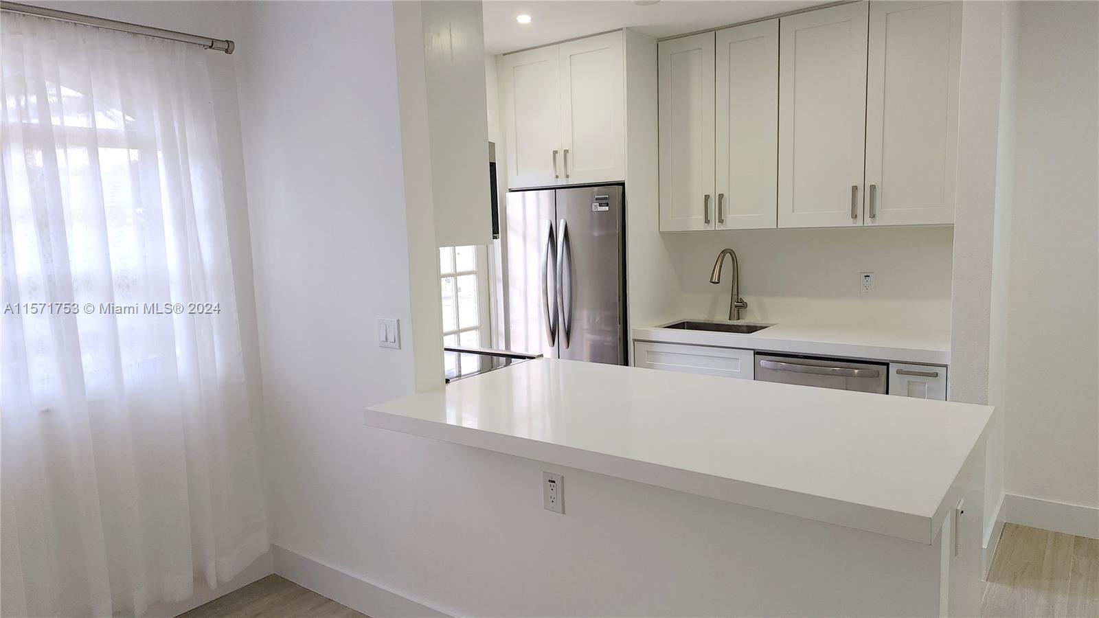 a kitchen with stainless steel appliances a refrigerator and white cabinets