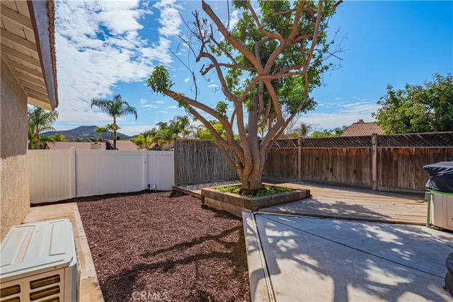 a view of a backyard with wooden fence and a large tree