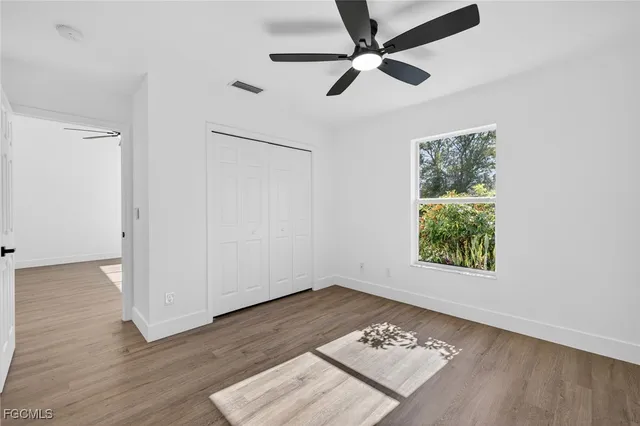 an empty room with wooden floor fan and windows