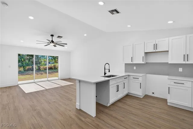 a open kitchen with white cabinets a sink dishwasher and a stove with wooden floors