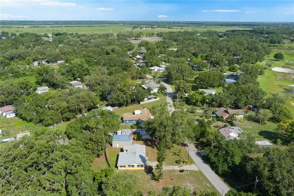 an aerial view of residential house with outdoor space and trees all around