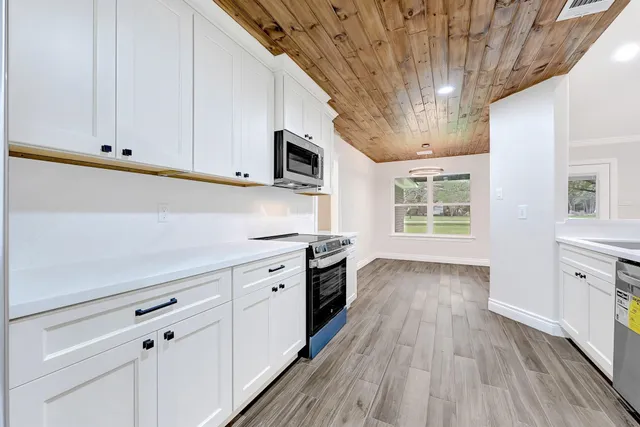 a kitchen with stainless steel appliances a white stove top oven cabinets and a wooden floor