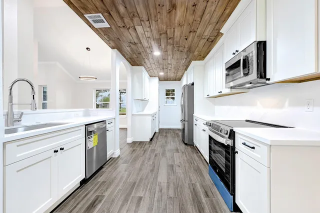 a kitchen with stainless steel appliances granite countertop a lot of counter space and wooden floors