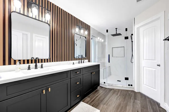 a spacious bathroom with a double vanity sink a mirror and a shower