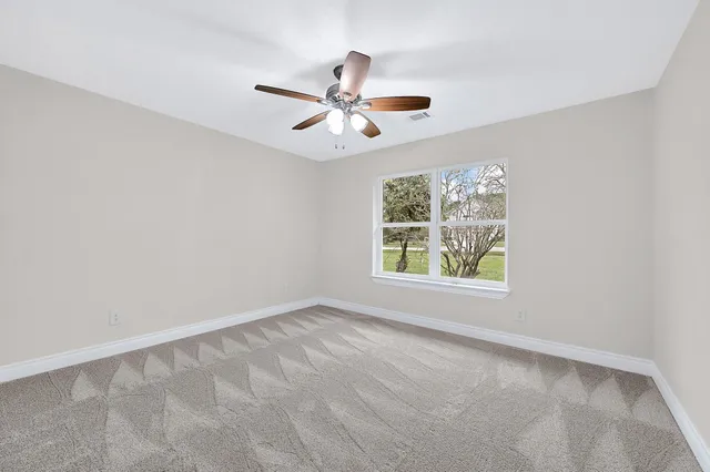 an empty room with windows and fan