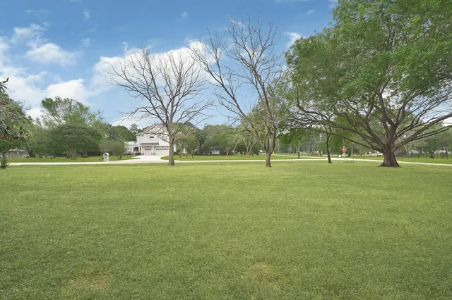 a white house with a big yard and large trees