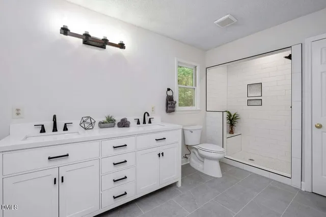 a spacious bathroom with a toilet a sink a mirror and a window