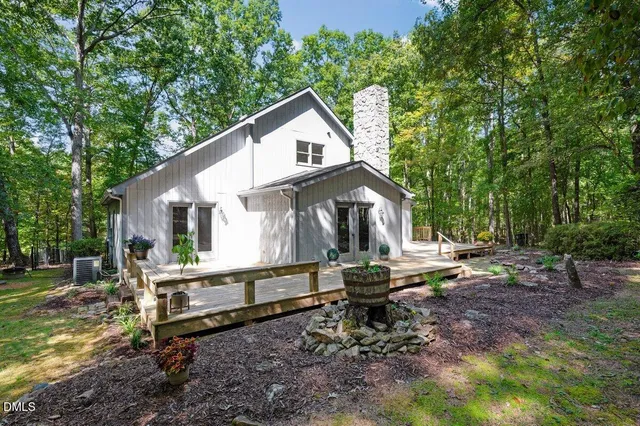 a view of a small house with backyard and chairs