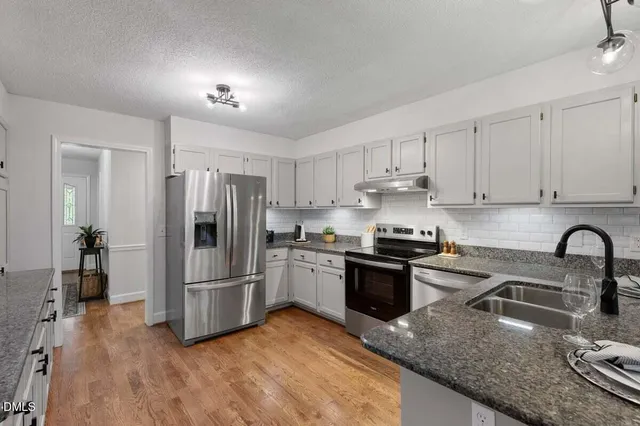 a kitchen with granite countertop a refrigerator stove and sink
