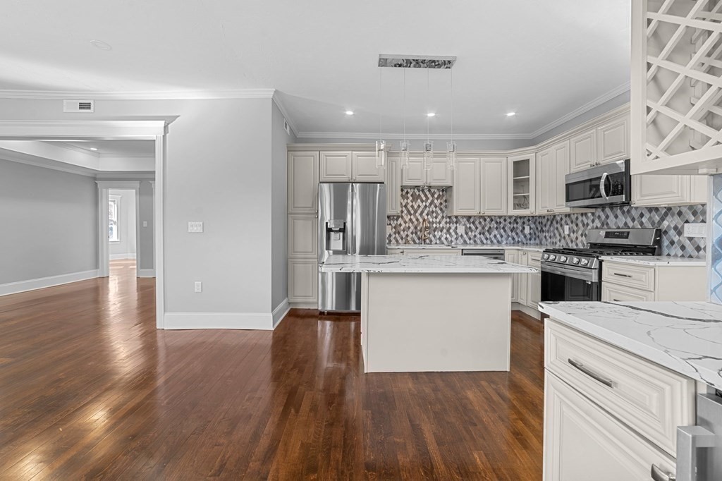 44 Bowdoin Street, Unit 2 Boston, MA 02124 - Photo 11 of 33 a kitchen with stainless steel appliances kitchen island wooden floors and white walls