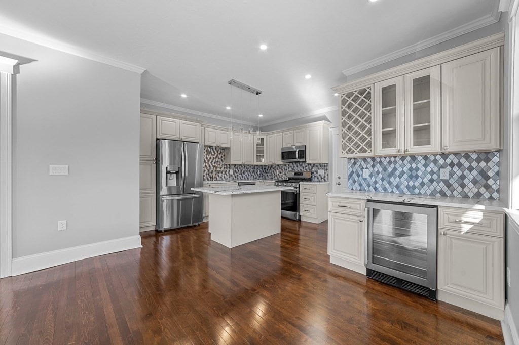 44 Bowdoin Street, Unit 2 Boston, MA 02124 - Photo 12 of 33 a kitchen with stainless steel appliances kitchen island wooden floors and white cabinets
