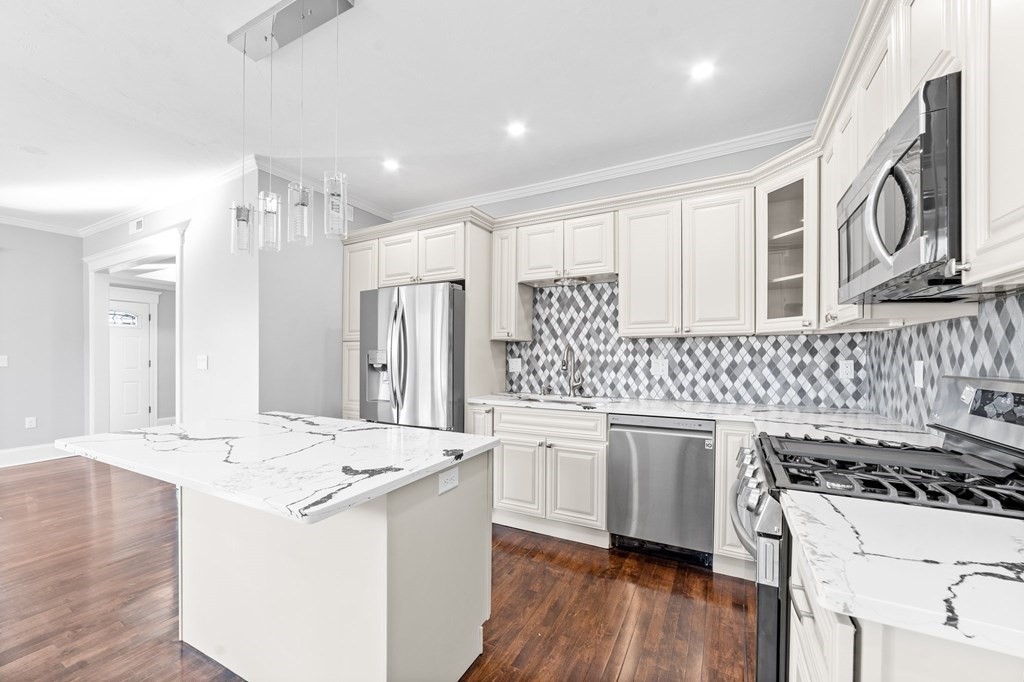 44 Bowdoin Street, Unit 2 Boston, MA 02124 - Photo 14 of 33 a kitchen with stainless steel appliances kitchen island hardwood floor sink stove and refrigerator