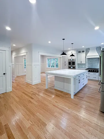 a large white kitchen with kitchen island and stainless steel appliances