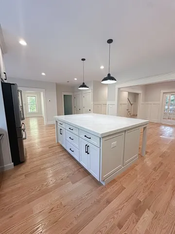 a large white kitchen with a large island oven a stove with wooden floors