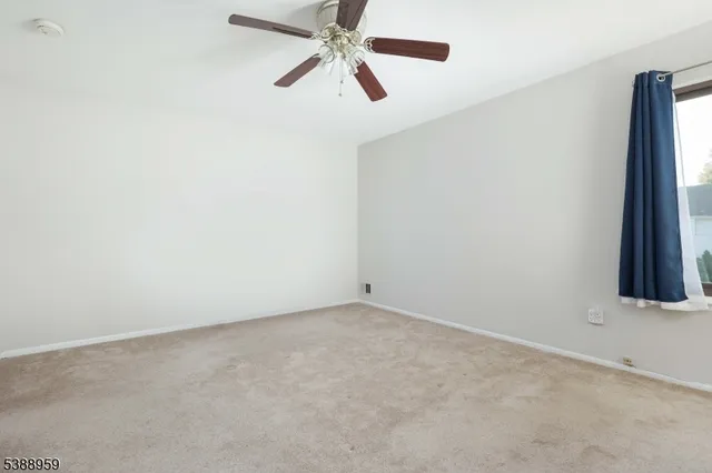 an empty room with a ceiling fan and a window