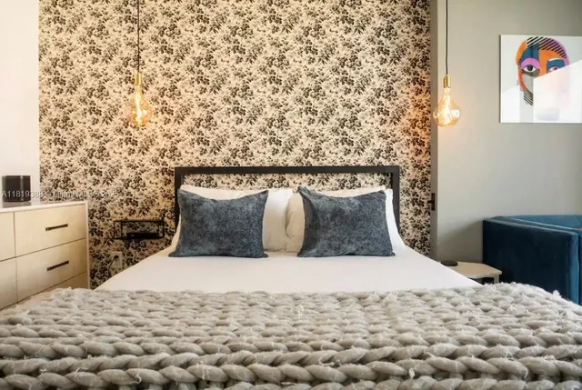 a large bed sitting in a bedroom next to a lamp next to a window